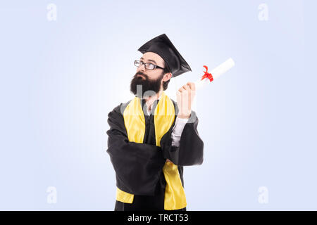 graduated man holding diploma over blue background serious face thinking about question, very confused idea Stock Photo