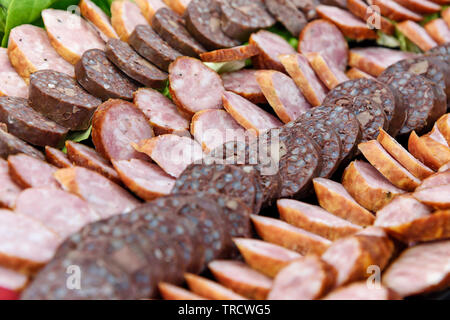 Sliced meat products and sausages on a plate in close-up ready to eat Stock Photo