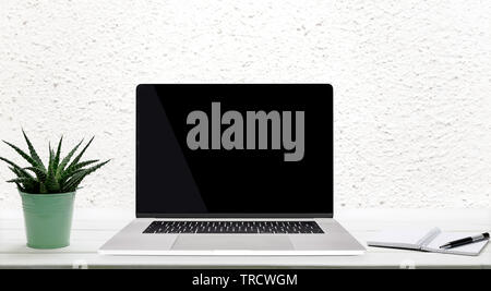 Moder worplace concept - generic silver laptop with a blank screen on a wooden table in the room. Stock Photo
