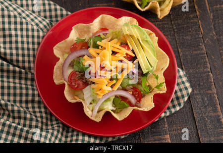 Taco Salad in a Crunch Corn Tortilla Bowl Isolated on a Wooden Table Stock Photo