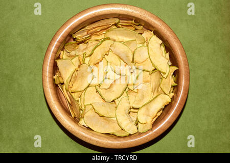 Homemade apple chips in the ceramic bowl natural healthy snack top angle view on the green background Stock Photo