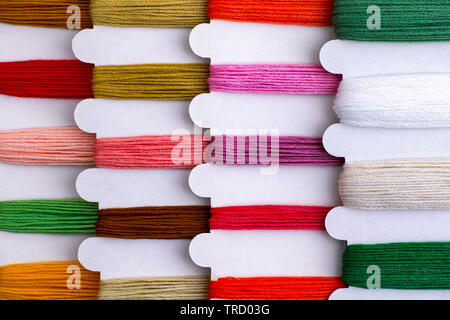 Colored embroidery threads on spools in a row ready for cross stitch. Close-up. Stock Photo