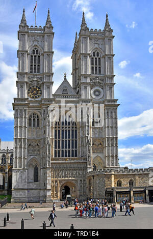 Group of summer sightseeing tourists outside entrance & shop at iconic west front of famous & historical Westminster Abbey church London England UK Stock Photo