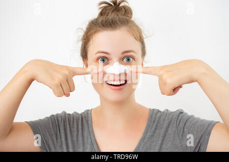 Young caucasian woman with white peel mask on her nose, removing blackheads Stock Photo