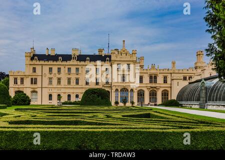 Lednice, Czech Republic - May 27 2019: Famous Lednice castle in South Moravia with yellow facade. Garden with green lawn, bush and flowers in foregrou Stock Photo