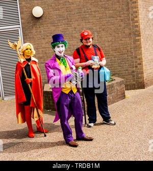 Great Yarmouth Comicon 2019 – The Joker, Mario and a super heroine outside the entrance of the Comicon event in the seaside town of Great Yarmouth Stock Photo