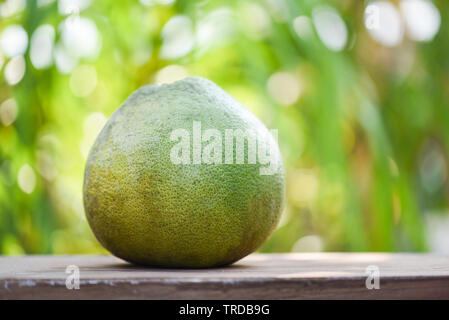 Fresh pomelo fruit on wooden table and green nature background Stock Photo