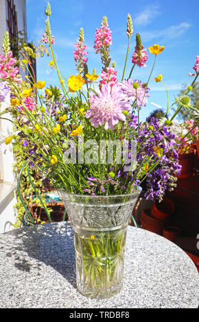 Wildflower bunch in a glass vase on the balcony table, home decoration Stock Photo