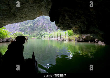 Tourists travel to visit natural landscapes through cave doors at Tam Coc National Park in Ninh Binh, Vietnam. Stock Photo