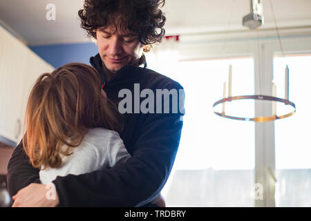 caucasian Young dad and toddler baby girl embracing at home, looking at each other in natural morning light. Stock Photo