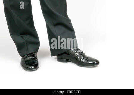 Close-up view of legs of a male dressed in a black suit with black shoes against white background Stock Photo