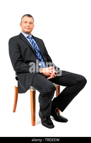 Portrait of a Businessman in a grey suit folding his hands while sitting on a chair Stock Photo