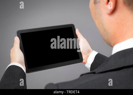 Portrait of a likeable Businessman in a black suit looking at a tablet he holds in his hands Stock Photo
