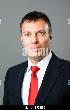 Portrait of a likeable Businessman in a black suit against grey background Stock Photo