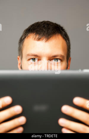 Portrait of a likeable Businessman in a black suit looking at a tablet he holds in his hands Stock Photo