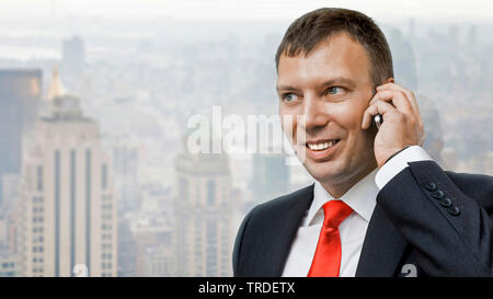 Portrait of a likeable Businessman in a black suit making a phone call against skyscrapers in the background Stock Photo