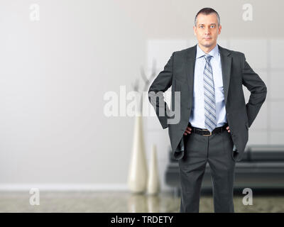 Portrait of a Businessman in a grey suit standing with hands in his hands on the hips Stock Photo