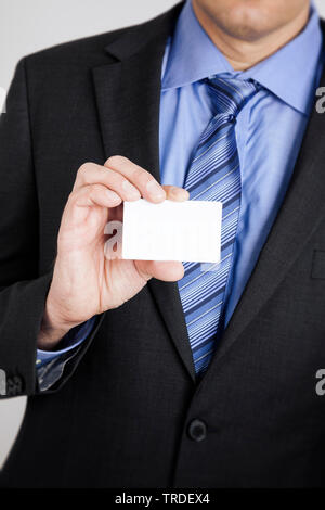Partial portrait of a Businessman in a grey suit holding an empty name card in his hand Stock Photo