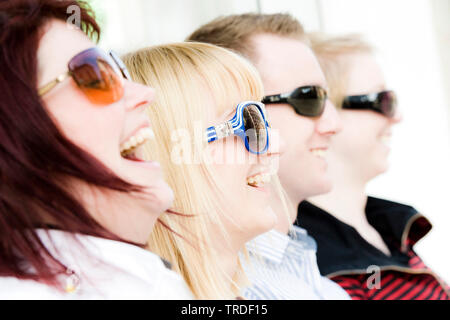 Group portrait/close up of 4 young persons wearing sunglasses sitting Stock Photo