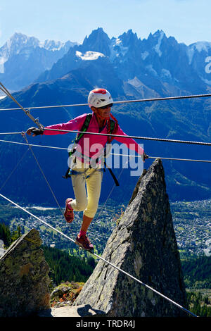 woman balancing on a tightrope, Via ferrata des Evettes, France, Savoie Stock Photo