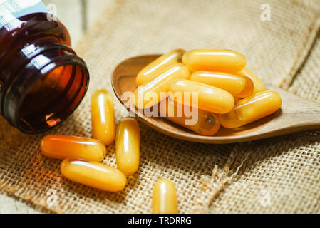 Royal jelly capsules in wooden spoon and sack background / Yellow capsule medicine or supplementary food from nature for health Stock Photo