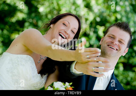 Bridal couple showing off their wedding rings after the ceremony and smiling Stock Photo