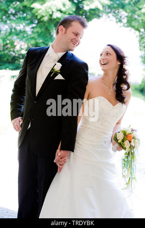 Wedding picture of a bridal couple holding hands and smiling outdoors Stock Photo