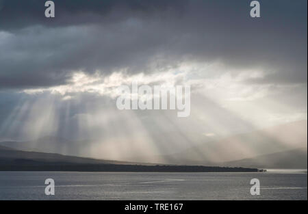 crepuscular rays breaking through the clouds over island Kvaloya, Norway, Troms, Tromsoe Stock Photo