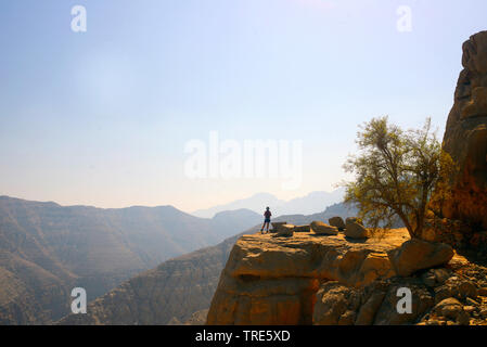 female wanderer standing on rocky plateau and enjoying the view, Oman, Musandam, Khasab Stock Photo