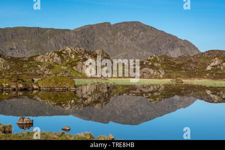 The Lakeland mountain of Pillar reflecting in the still waters of Innominate Tarn on an early summer morning Stock Photo