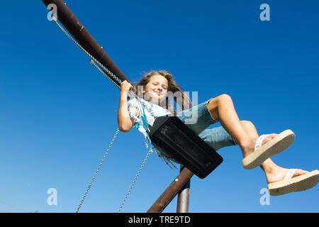 Young girl playing on pending swing Stock Photo