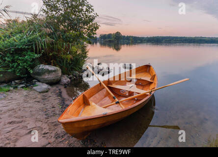 wooden rowing boat on the lakefront of the Bistensee in the evening, Germany, Schleswig-Holstein, Kreis Eckernfoerde Stock Photo
