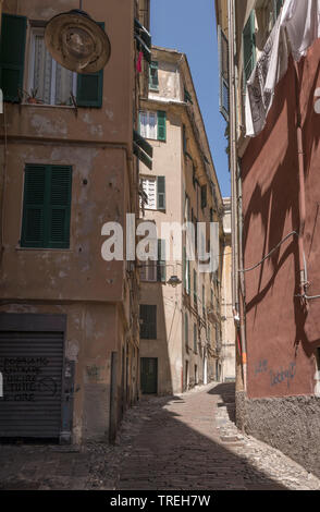 cityscape with high buildings on narrow alley  in sea town historical center . Shot on a sunny spring day at Genova, Liguria, Italy Stock Photo