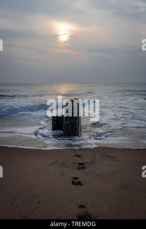 Sunrise over rock and footprints of nature lover in sandy beach of pondicheery india. Stock Photo