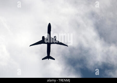 Airplane silhouette in the sky close up. Commercial plane taking off on background of white clouds