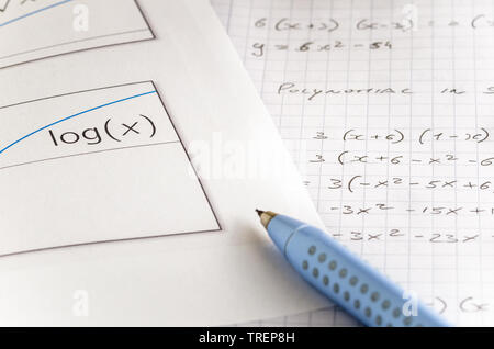 Close view of a sheet of paper with a logarithmic Graph and a open notebook with handwritten mathematics equations Stock Photo