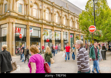 Locals and Tourists strolling around pedestrian zone lined with shops and restaurants in Harrogate  city centre, Yorkshire, UK. on a cloudy autumn day. Stock Photo