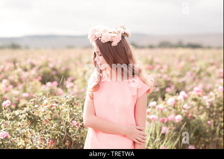 Beautiful teenage girl 14-16 year old wearing trendy dress and wreath with roses outdoors. Looking away. Stock Photo