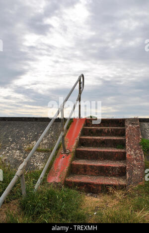 Steps leading up to the promenade set against a grey cloudy sky in Borth, Wales Stock Photo