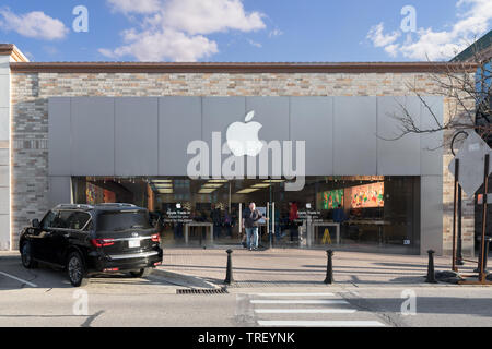An Apple Store in the middle of downtown Naperville in the evening. The store features cell phones, computers, and other technology gadgets. Stock Photo
