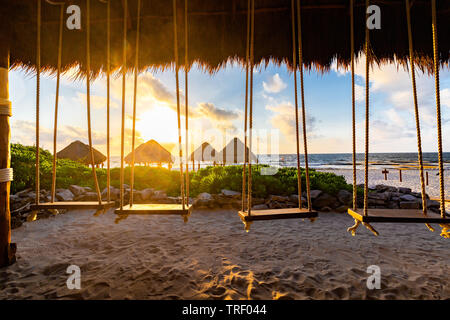Swings hanging in a hut at the Valentin Imperial Maya all inclusive resort looking out over the ocean and morning sunrise. Stock Photo