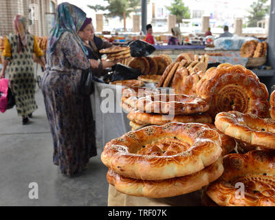 Margilan, Fergana Valley, Uzbekistan  Woman selling Uzbek bread, non or lepeshka, which is round and flat and is baked in tandyr, Stock Photo