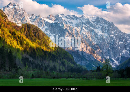 Sunset in the valley, Logarska Dolina, Slovenia. Majestic late sunlight illuminates distant mountain range and peaks of near steep slopes of the hill. Stock Photo