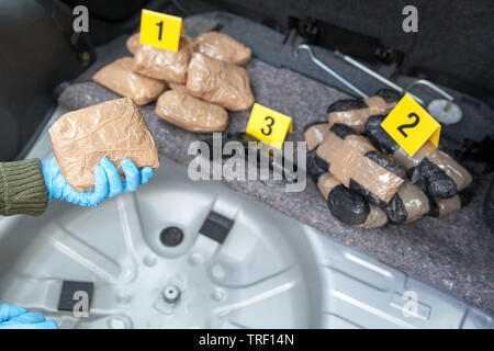 Police officer holding drug package discovered in the trunk of a car Stock Photo