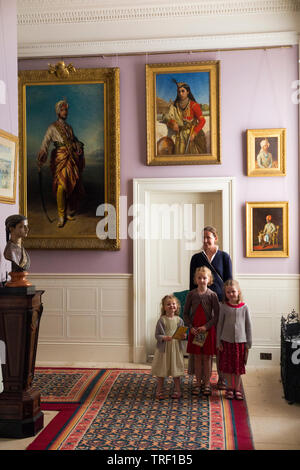 Mother / mum and three children complete on a family holiday / vacation with portrait paintings in the Durbar Corridor at Osborne House on the Isle of Wight. UK. (99) Stock Photo