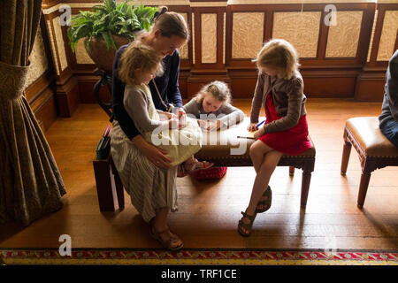 Mother / mum and three children complete mystery trail challenge activity questionnaire in the Durbar Room at Osborne House on the Isle of Wight. UK. Stock Photo