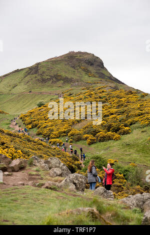 Large group of people walk up the side of Arthur's Seat in Edinburgh, Scotland