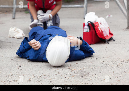 First aid training - workplace accident at a construction site, helping a n injured worker Stock Photo