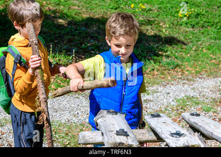 Discovering nature with the kids in springtime near Ofterschwang in Upper Allgäu, playing a wooden xylophone Stock Photo