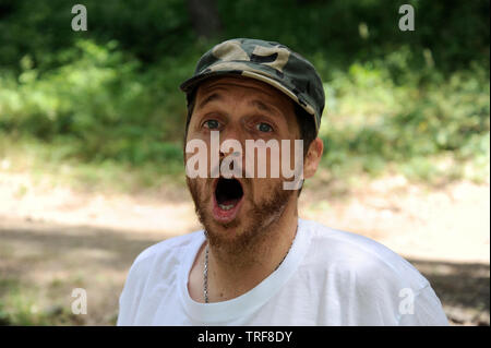 Outdoors horizontal portrait of happy hiker young man with red beard, feel good after hiking in forest. Traveler bearded male smiling and feel happy d Stock Photo